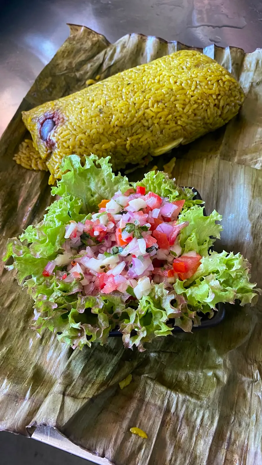 Juane de arroz envuelto en hoja de bijao con salsa criolla