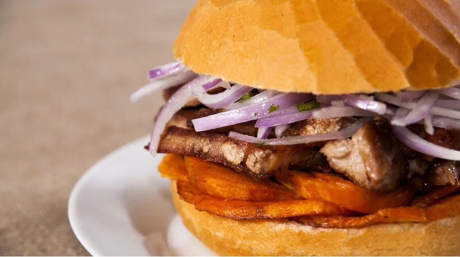Pan con chicharrón, camote y cebolla en salsa criolla