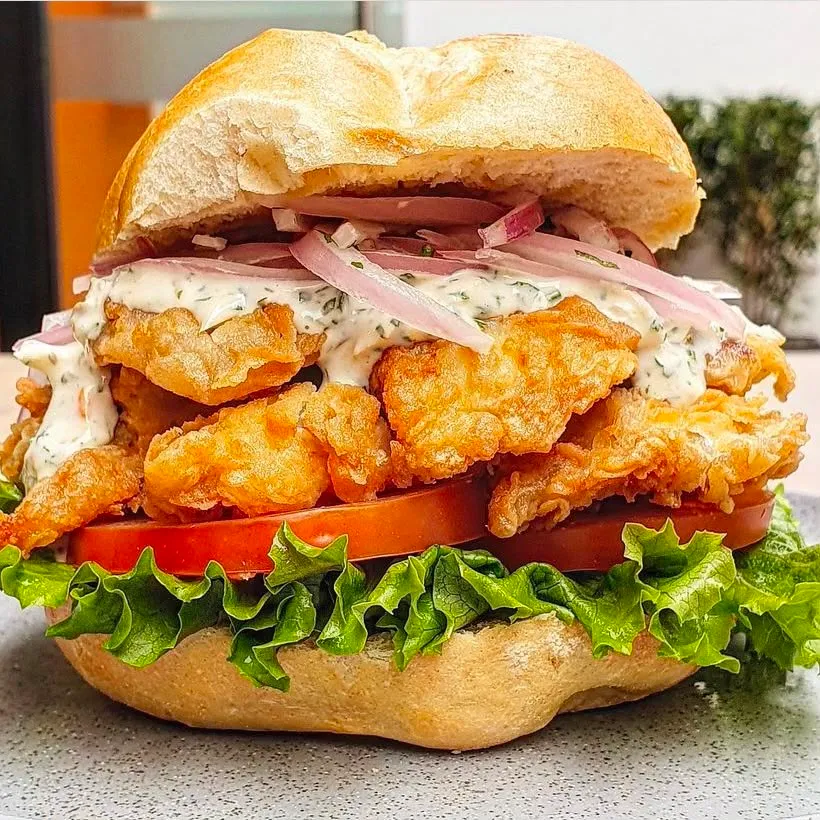 Sándwich de pescado apanado con lechuga y tomate