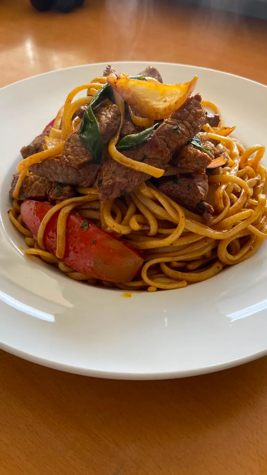 Tallarín saltado de carne con cebolla y tomate
